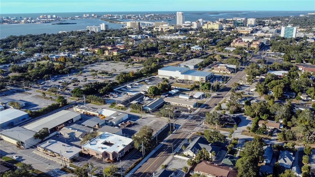 An aerial view shows a commercial area with buildings, parking lots, and distant waterfront cityscapes — 1201 S MYRTLE AVENUE, CLEARWATER, FL