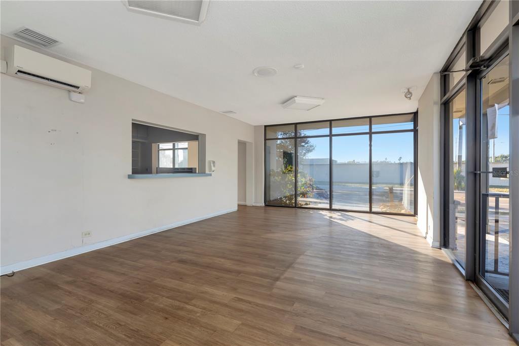 An empty commercial space features wood-look flooring, a service window, and floor-to-ceiling glass windows — 1201 S MYRTLE AVENUE, CLEARWATER, FL