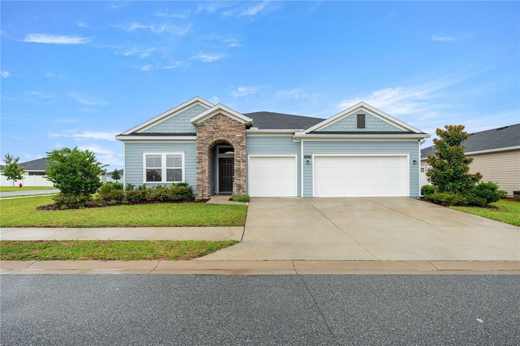 A light blue house with a stone entryway and a three-car garage — 9332 SW 58TH CIRCLE, OCALA, FL