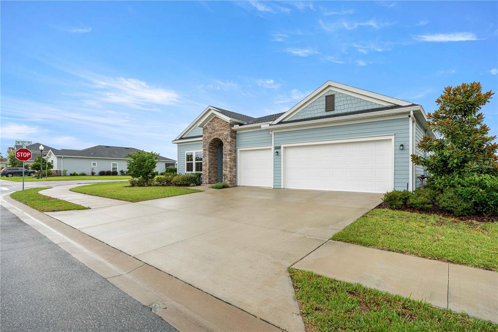 A light blue single-story house features a stone-accented entryway and a two-car garage — 9332 SW 58TH CIRCLE, OCALA, FL