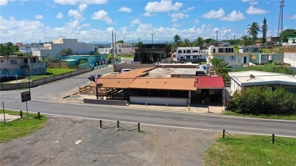 An aerial view shows a commercial building with a brown roof beside a paved road — Km 3.3 CARR 684, BARCELONETA, PR