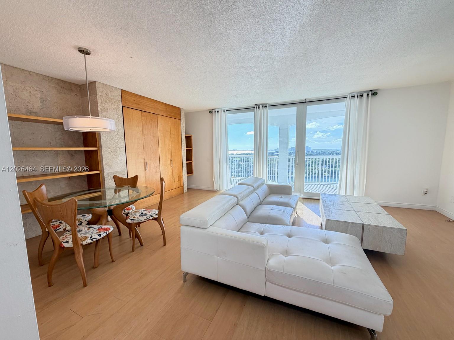 A living and dining area features a white sectional sofa, glass table, and balcony view — 5401 Collins Ave # 1022, Miami Beach FL 33140, MIAMI BEACH, FL