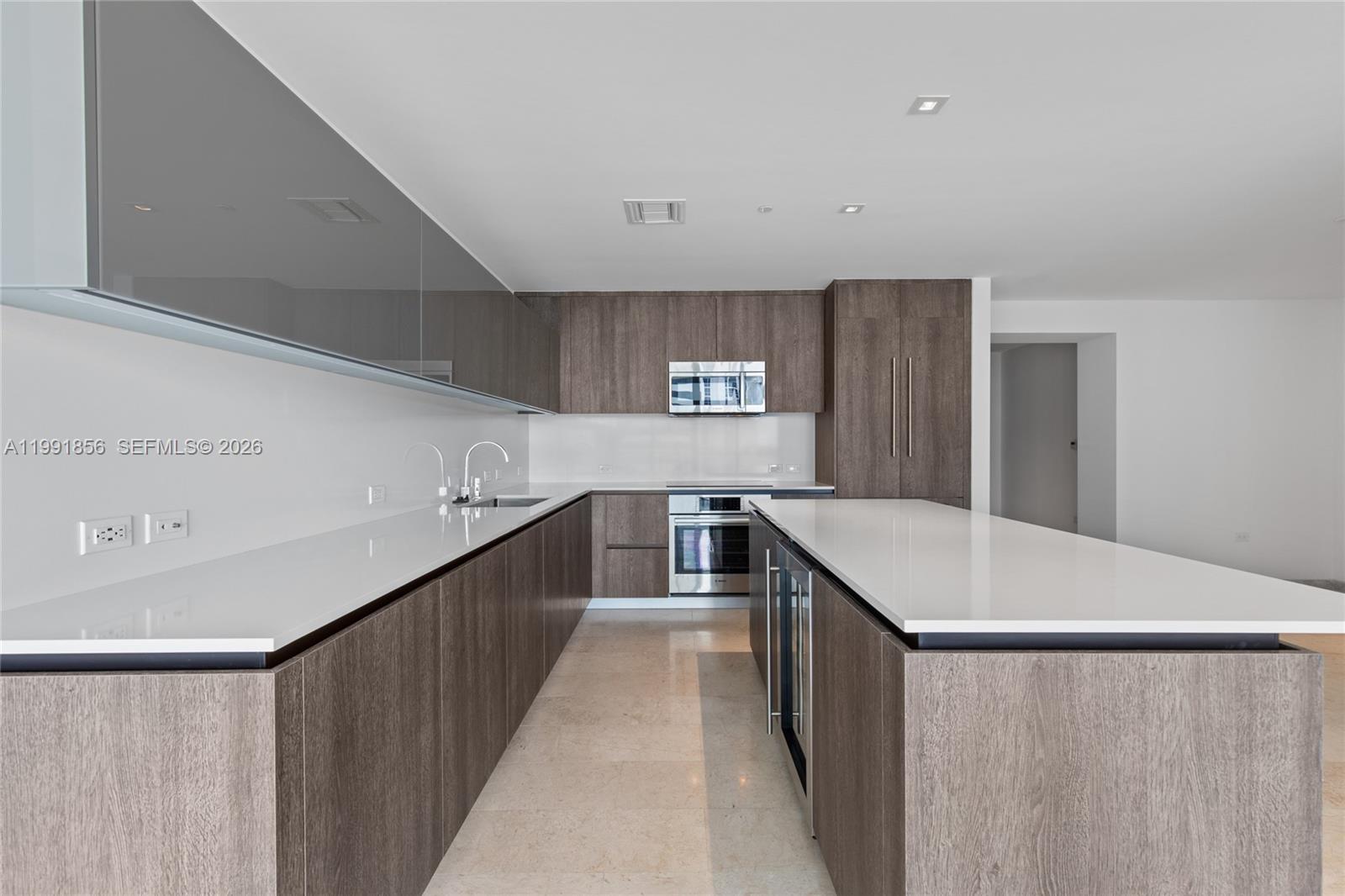 A modern kitchen features dark wood cabinetry, white countertops, stainless steel appliances, and tile flooring — 88 SW 7th St # 904, Miami FL 33130, MIAMI, FL
