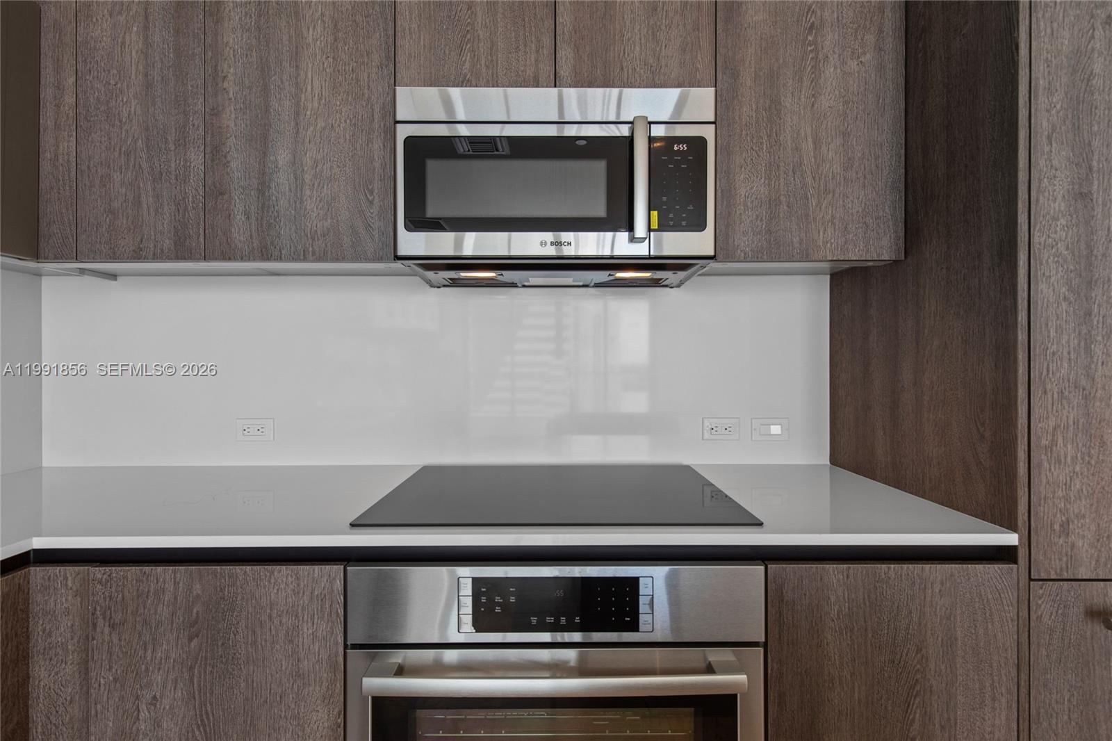 A modern kitchen features dark wood cabinets, a stainless steel microwave, and a glass cooktop — 88 SW 7th St # 904, Miami FL 33130, MIAMI, FL