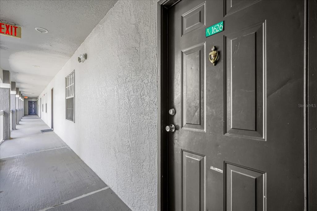 A dark brown apartment door with a brass knocker sits along an outdoor concrete walkway — 13803 FAIRWAY ISLAND DRIVE UNIT 1626, ORLANDO, FL