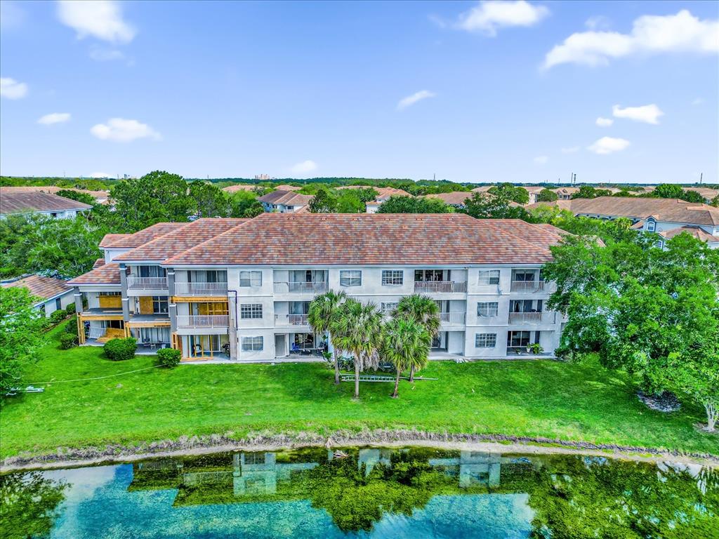 An aerial view of a multi-story apartment building with a tiled roof near a pond — 13803 FAIRWAY ISLAND DRIVE UNIT 1626, ORLANDO, FL