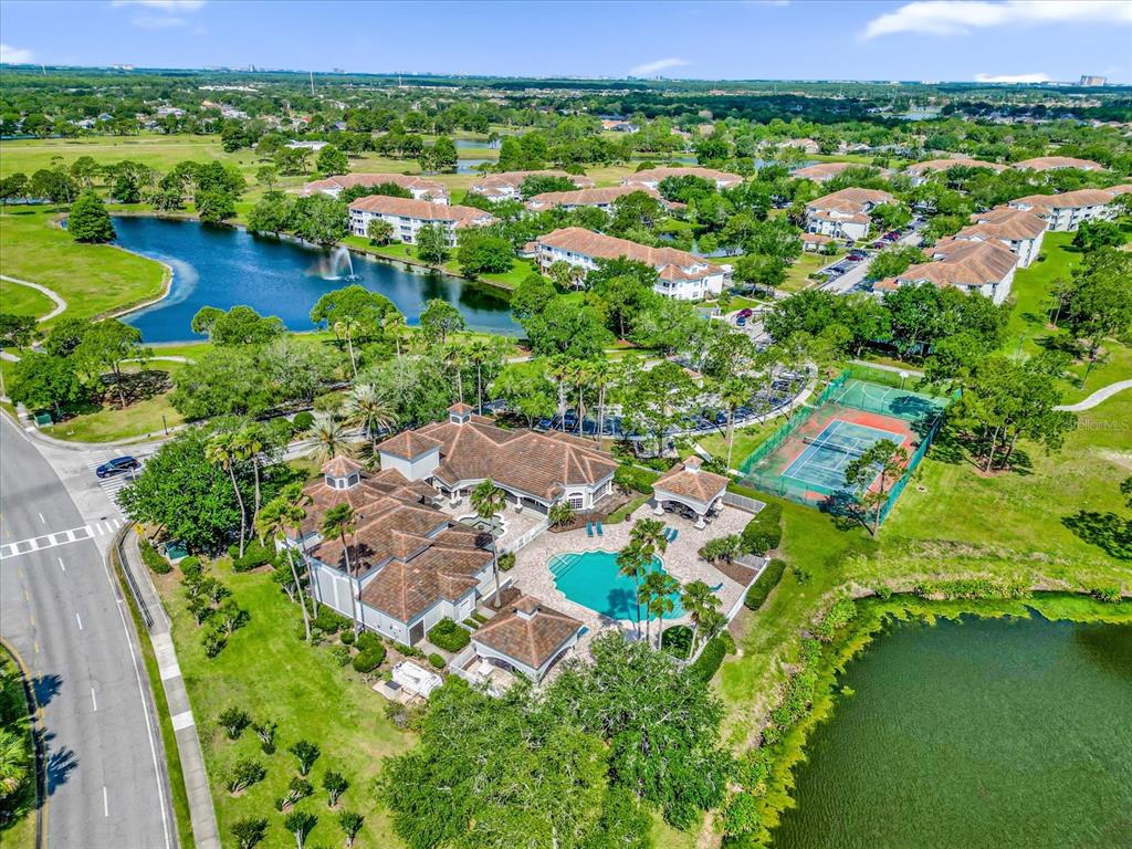An aerial view shows a clubhouse with a pool, tennis court, and surrounding residential buildings — 13803 FAIRWAY ISLAND DRIVE UNIT 1626, ORLANDO, FL