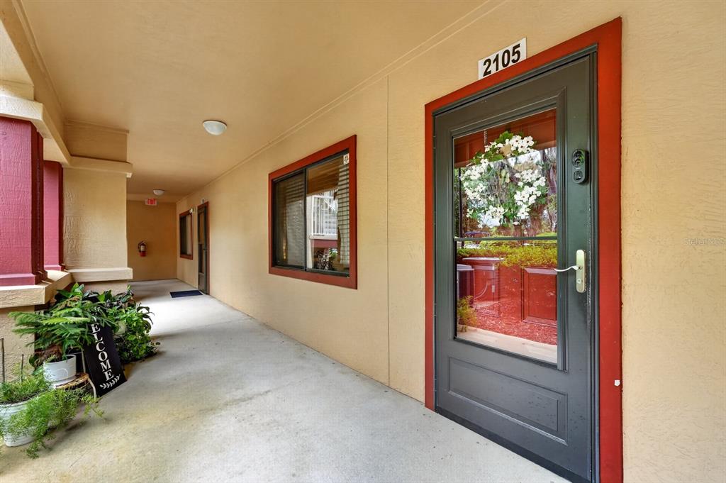 An exterior view of a covered apartment walkway featuring a front door numbered 2105 — 99 BROAD RIVER PLACE UNIT 2105, WELAKA, FL