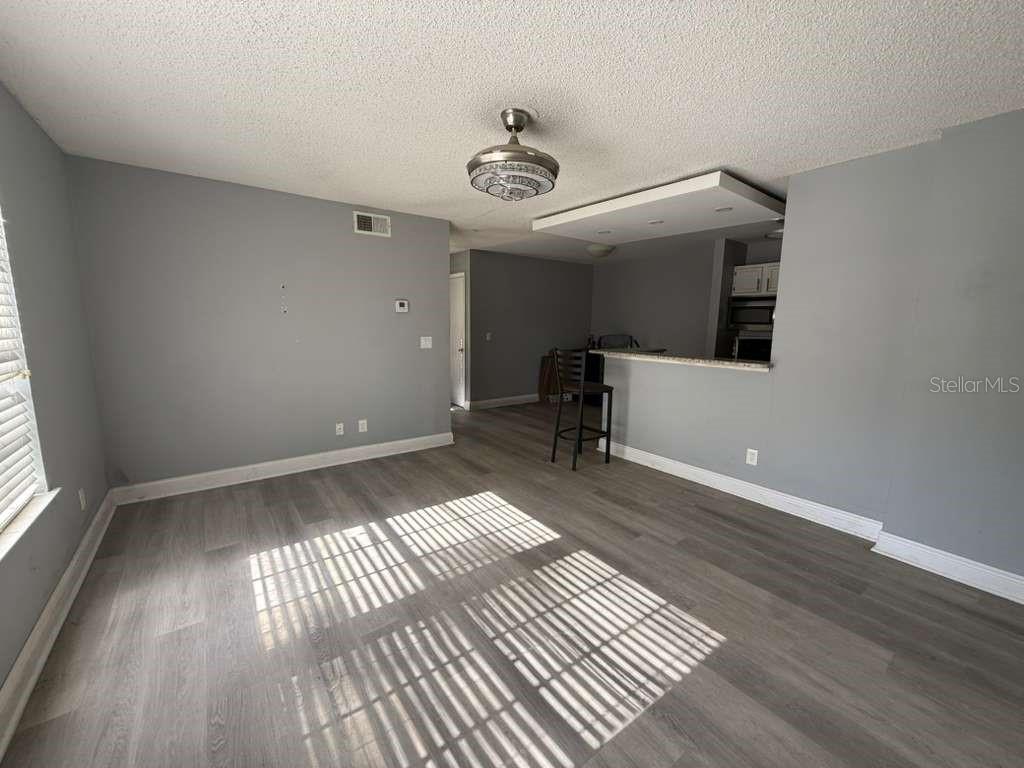 A living room with grey walls, wood-look flooring, and an open kitchen with a breakfast bar — 6094 WESTGATE DRIVE UNIT 101, ORLANDO, FL