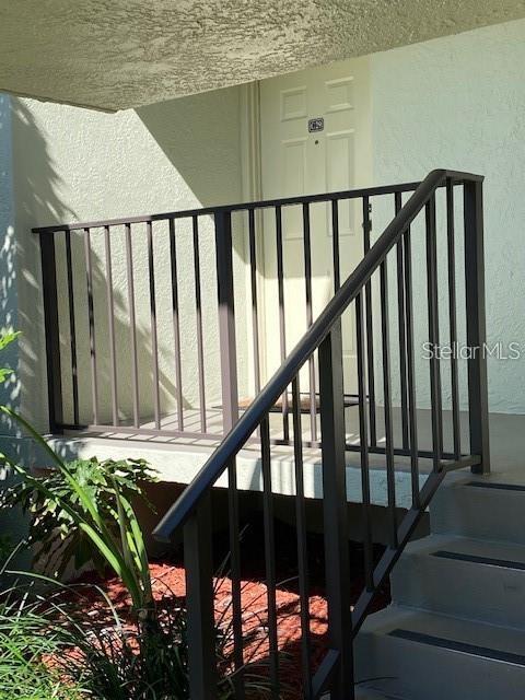 A metal railing borders the concrete steps and landing leading to a residential front door — 1515 S PINELLAS BAYWAY S S UNIT 29, TIERRA VERDE, FL