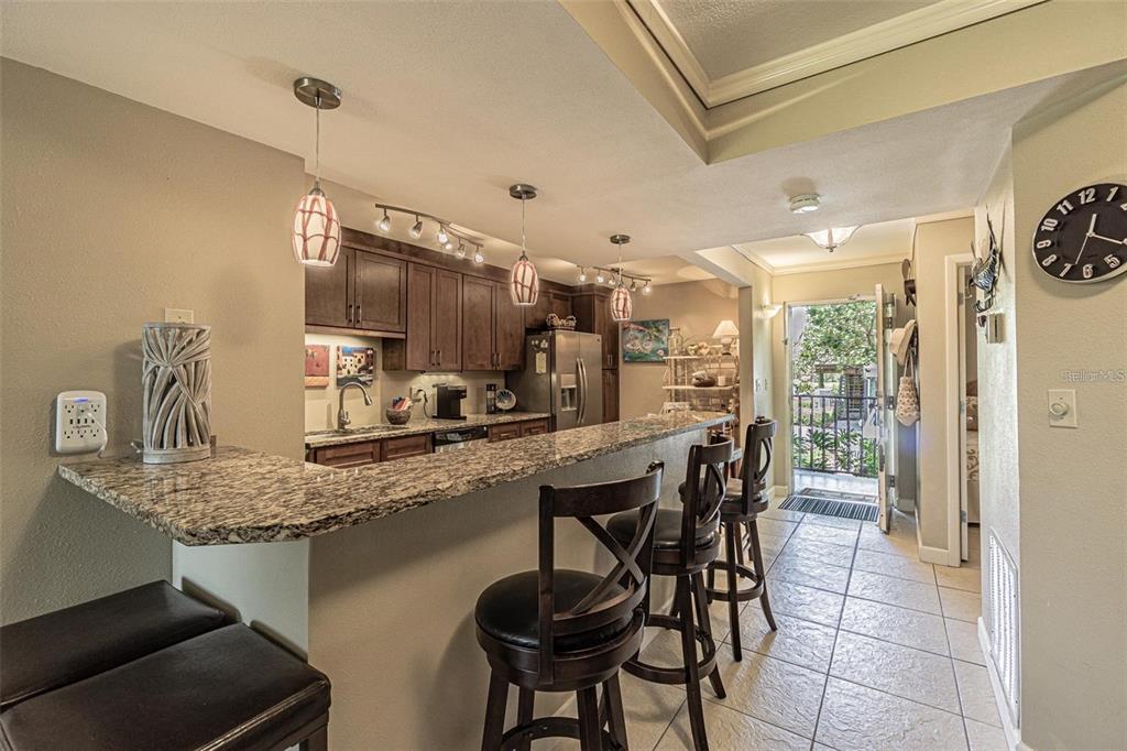 A kitchen with dark wood cabinets, granite countertops, and a breakfast bar with bar stools — 1515 S PINELLAS BAYWAY S S UNIT 29, TIERRA VERDE, FL
