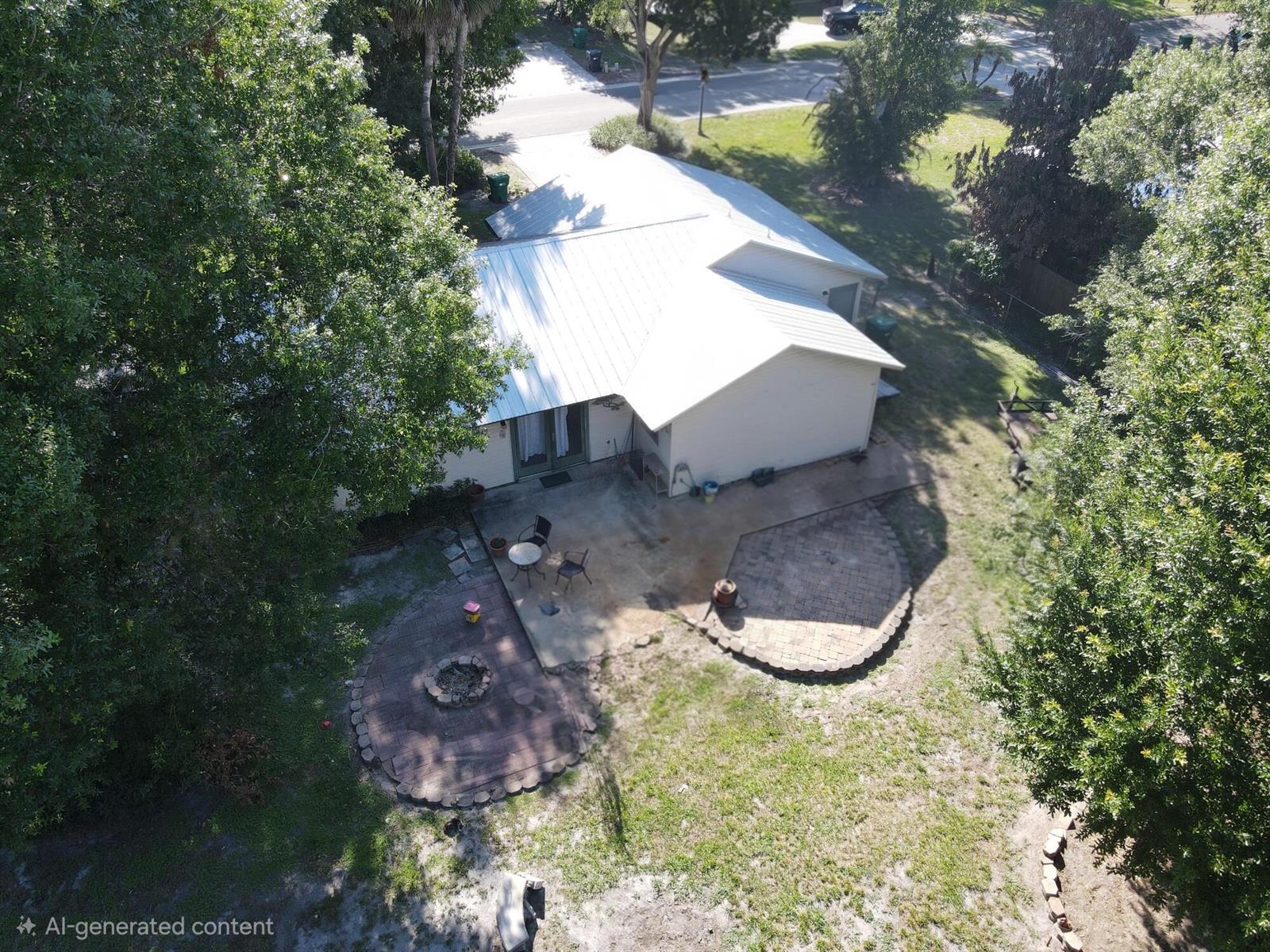 An aerial view of a house with a metal roof, concrete patio, and circular fire pit — 1396 SW 19th Terrace, Okeechobee FL 34974, OKEECHOBEE, FL