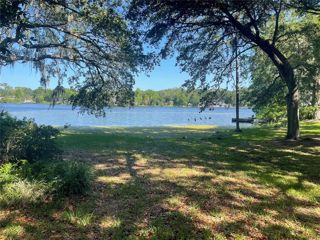 A gated entrance to a residential community features a guardhouse, metal fencing, and mature trees — 4965 PURITAN CIRCLE UNIT 401, TAMPA, FL