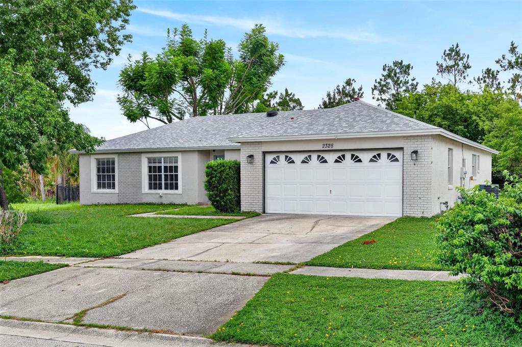A single-story house with a white brick facade, a two-car garage, and a concrete driveway — 2328 CLEMENTINE TRAIL, CLERMONT, FL