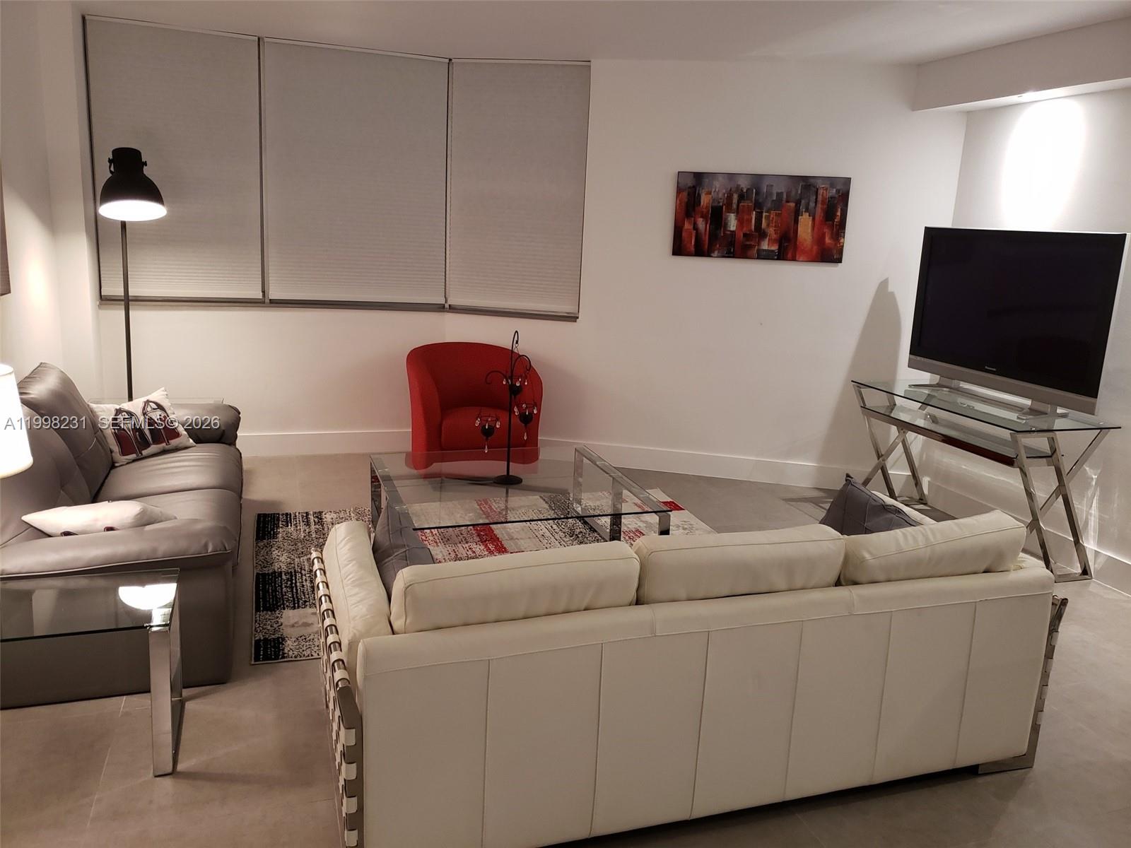 A living room features a white sofa, a gray sofa, a glass coffee table, and television — 3301 NE 5th Ave # 507, Miami FL 33137, MIAMI, FL