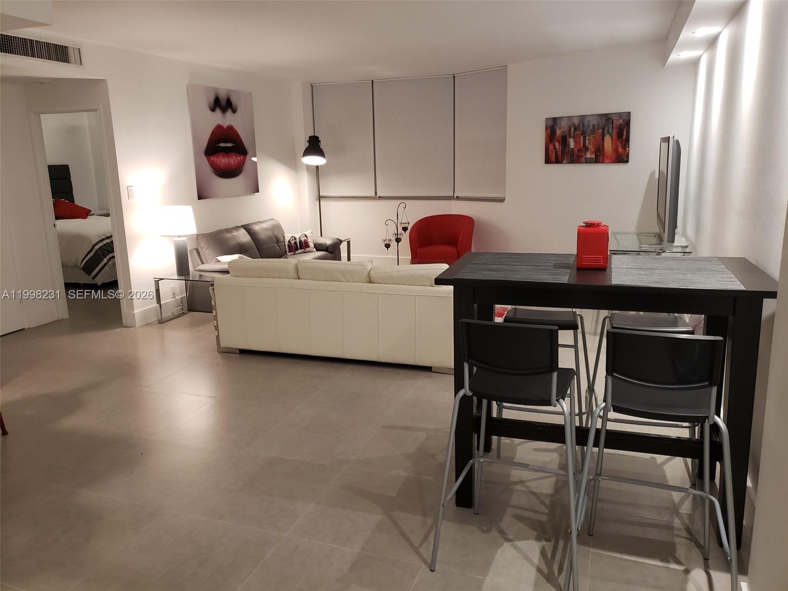 A living and dining area features a white sofa, a black dining set, and tile flooring — 3301 NE 5th Ave # 507, Miami FL 33137, MIAMI, FL