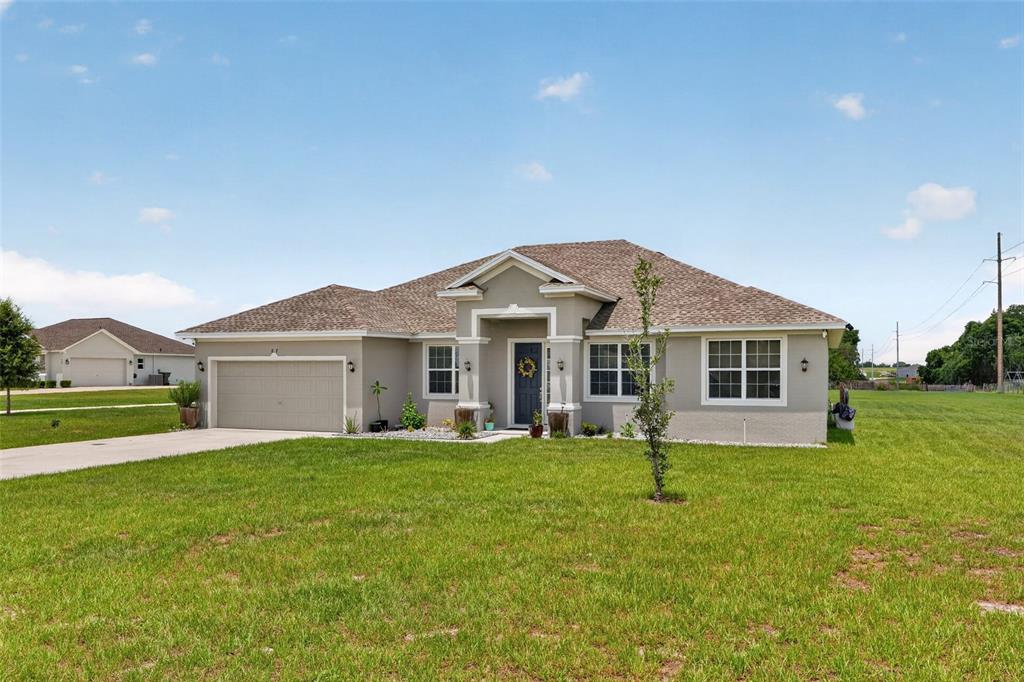 A single-story house with a beige stucco exterior, a two-car garage, and a front porch — 837 LIAM LANE, BARTOW, FL