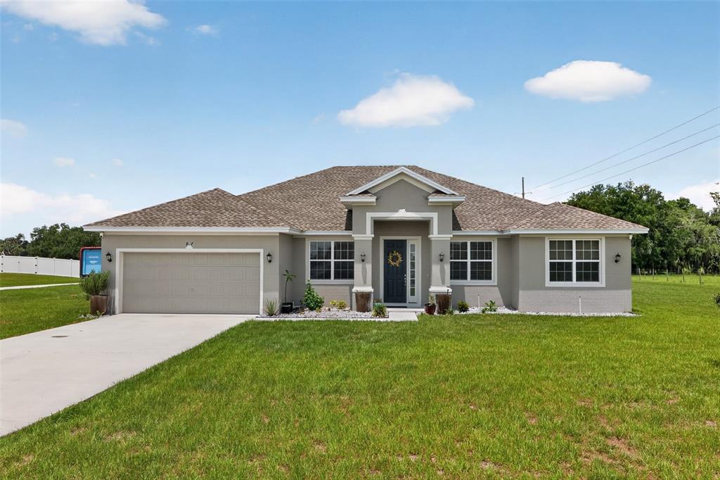 A single-story house with a gray stucco exterior, a two-car garage, and a front porch — 837 LIAM LANE, BARTOW, FL