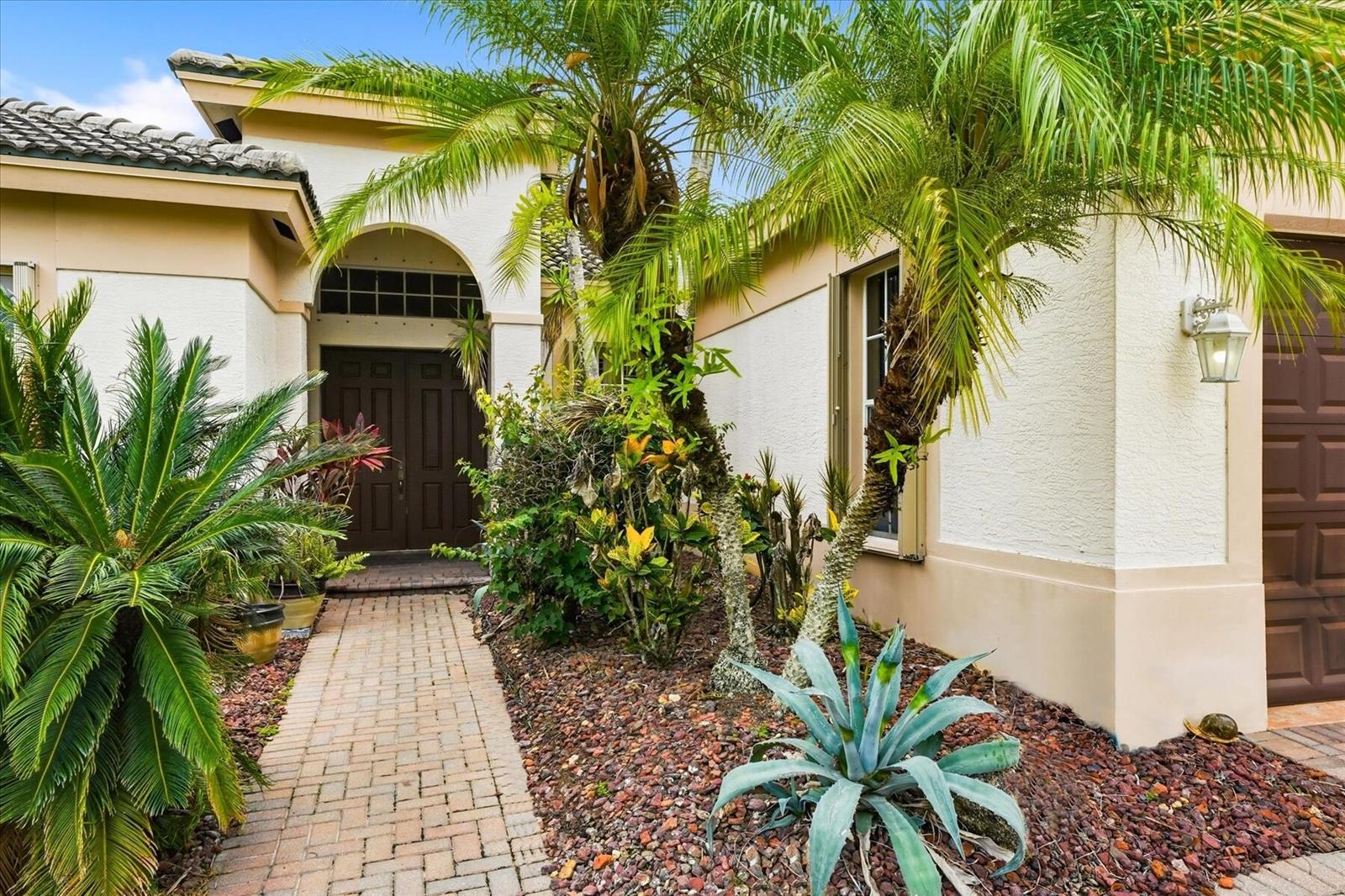 The exterior of a house features a brick walkway, palm trees, and a front entrance — 970 Amethyst Drive, Vero Beach FL 32968, VERO BEACH, FL