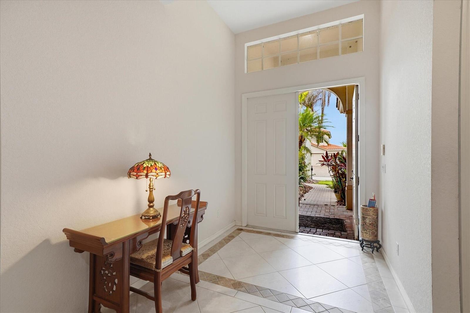 An entryway with tile flooring, a wooden desk, a stained-glass lamp, and an open door — 970 Amethyst Drive, Vero Beach FL 32968, VERO BEACH, FL