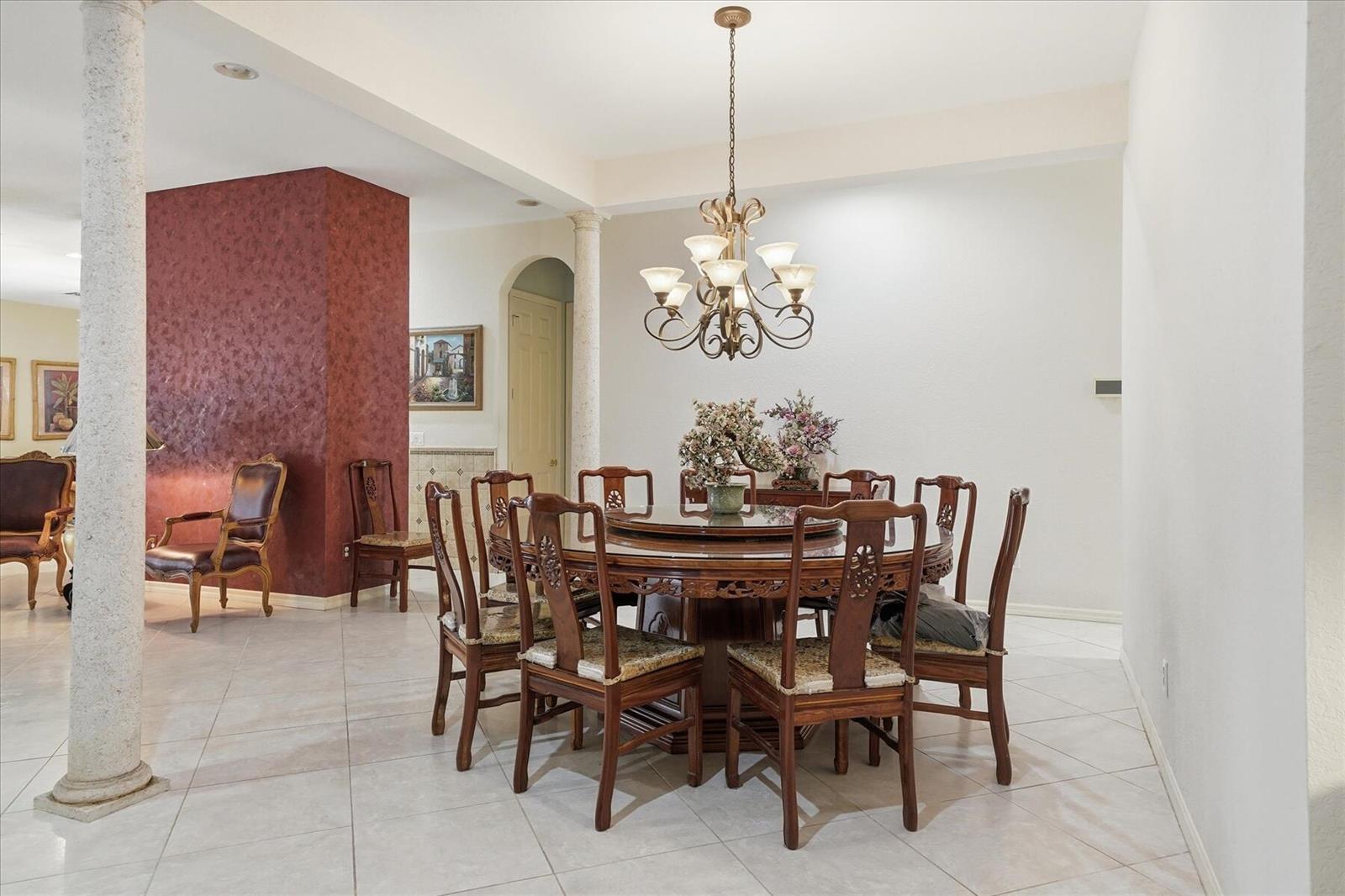 A dining room features a round wooden table with chairs under a chandelier and columns — 970 Amethyst Drive, Vero Beach FL 32968, VERO BEACH, FL