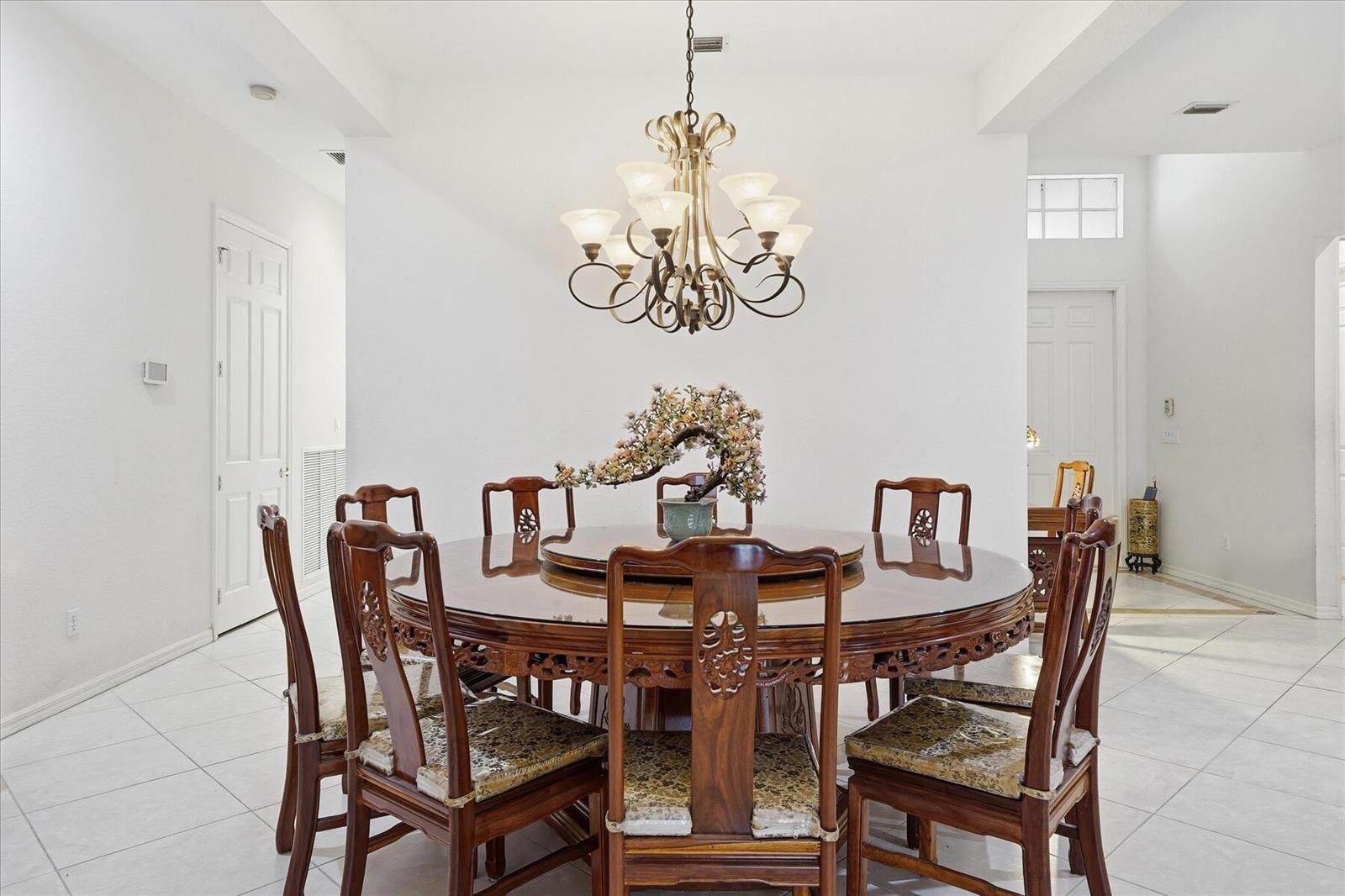 A dining room features a round wooden table with chairs and a decorative chandelier — 970 Amethyst Drive, Vero Beach FL 32968, VERO BEACH, FL