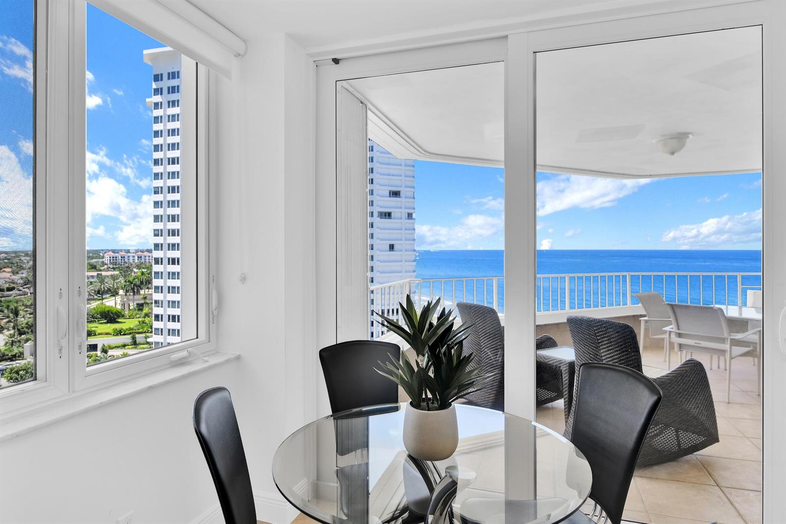 A dining area with a glass table overlooks a balcony and the ocean — 550 S Ocean Boulevard # 1003, Boca Raton FL 33432, BOCA RATON, FL