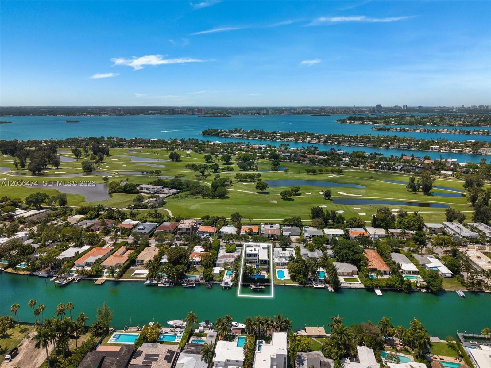 An aerial view shows a waterfront house with a pool along a canal and golf course — 470 S Shore Dr, Miami Beach FL 33141, MIAMI BEACH, FL