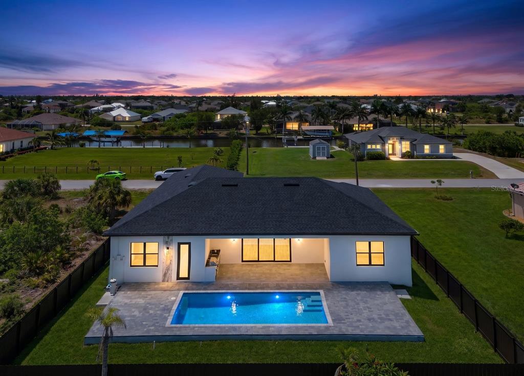 An aerial view of a single-story house with a backyard pool at sunset — 15301 ACORN CIRCLE, PORT CHARLOTTE, FL