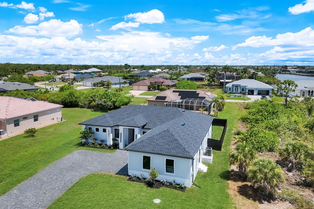 An aerial view shows a single-story house with a dark shingled roof and driveway — 15301 ACORN CIRCLE, PORT CHARLOTTE, FL