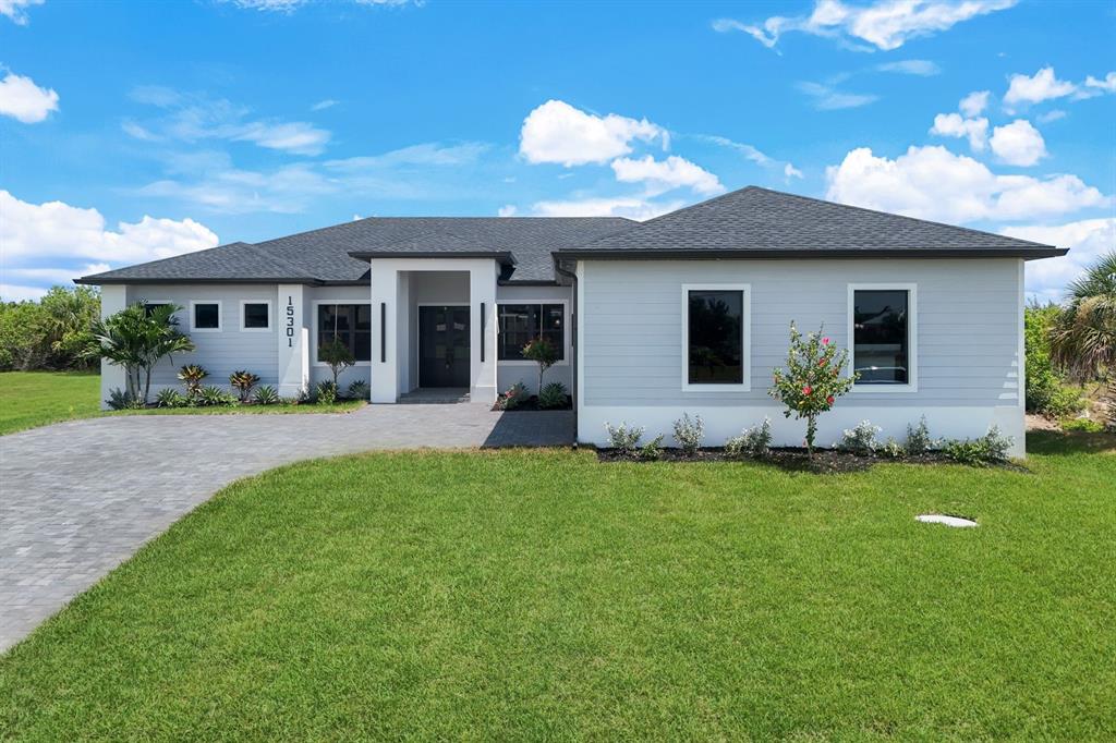 A single-story house with light gray horizontal siding, a dark shingled roof, and paved driveway — 15301 ACORN CIRCLE, PORT CHARLOTTE, FL