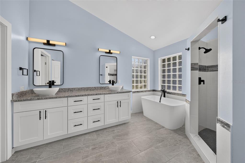 A bathroom features a double vanity with vessel sinks, a freestanding tub, and a walk-in shower — 428 SW 19TH AVENUE, CAPE CORAL, FL