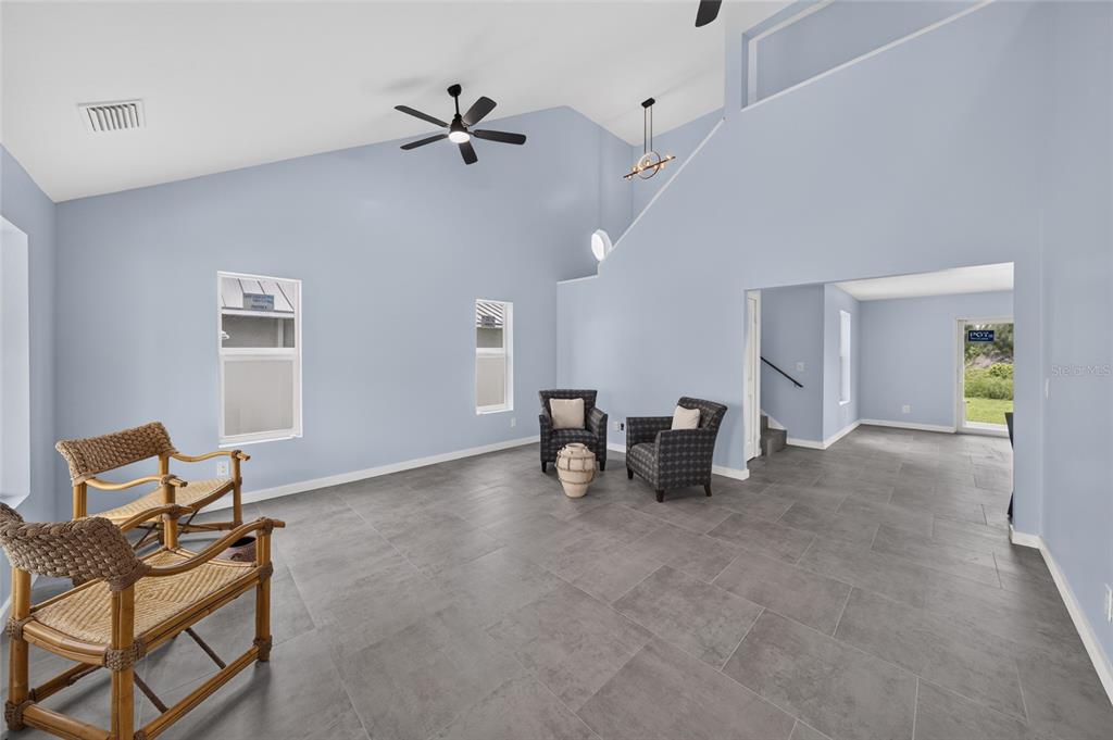 A spacious living room features light blue walls, gray tile flooring, and a vaulted ceiling — 428 SW 19TH AVENUE, CAPE CORAL, FL