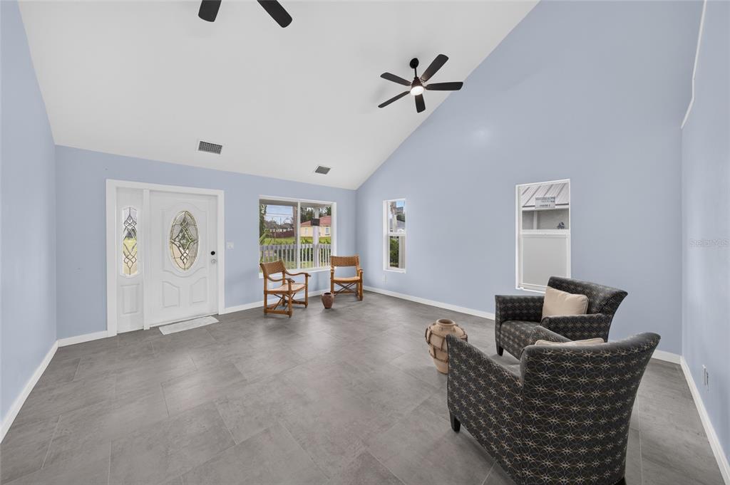 A living room with light blue walls, gray tile flooring, and a vaulted ceiling — 428 SW 19TH AVENUE, CAPE CORAL, FL