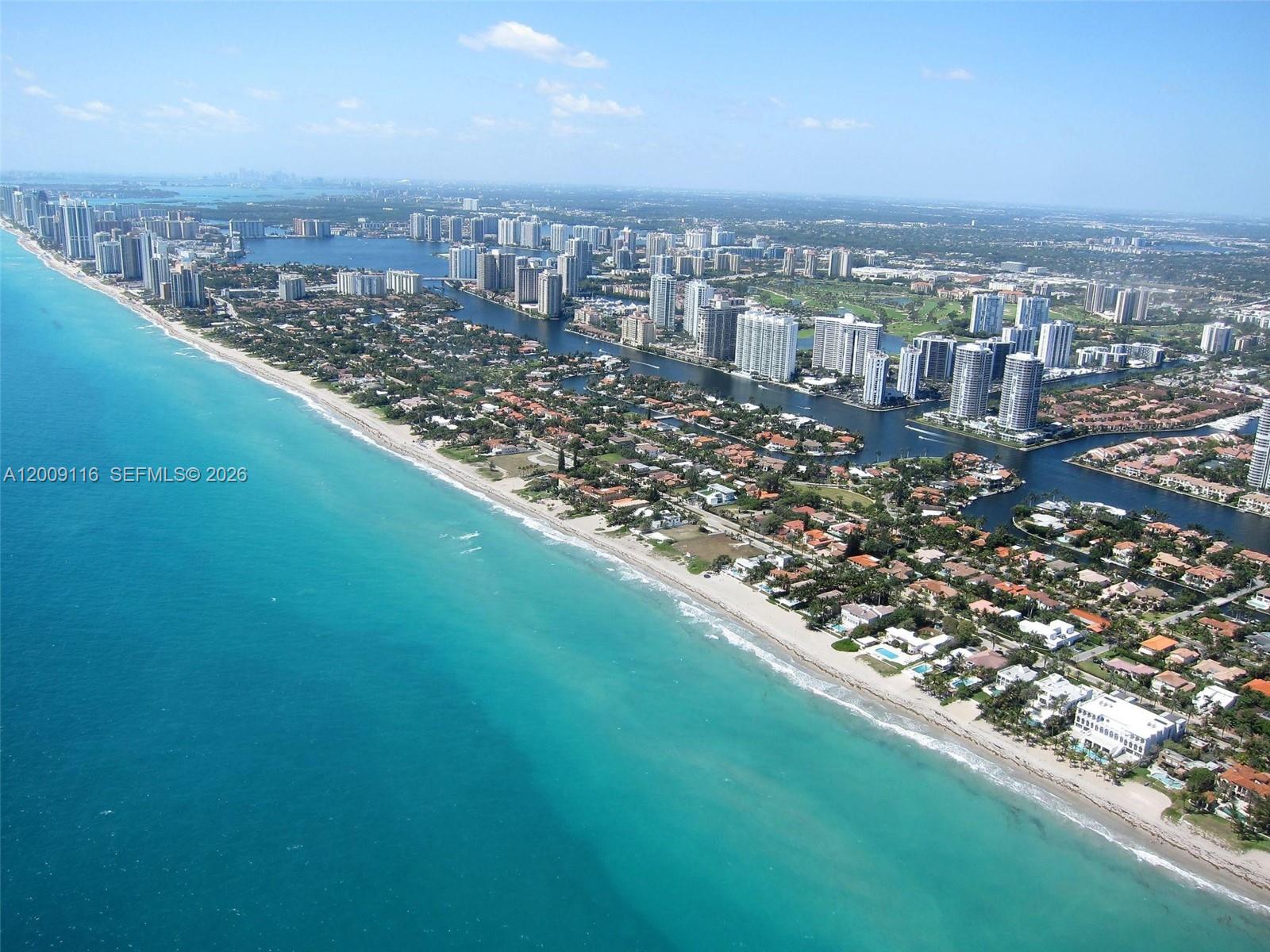 An aerial view shows a coastal city with high-rise buildings, residential homes, and turquoise water — 185 Ocean Blvd, Golden Beach FL 33160, GOLDEN BEACH, FL