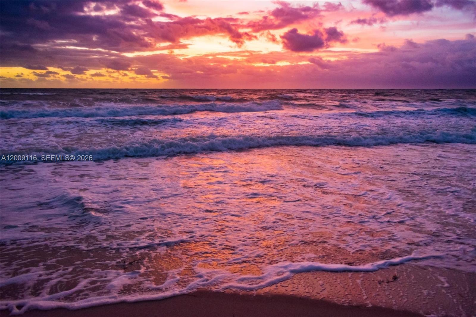 A vibrant sunset illuminates the ocean waves washing onto a sandy beach — 185 Ocean Blvd, Golden Beach FL 33160, GOLDEN BEACH, FL