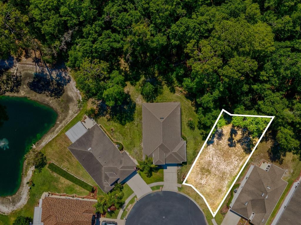 An aerial view shows a vacant residential lot outlined in white next to two houses — 11444 MERGANSER WAY, NEW PORT RICHEY, FL