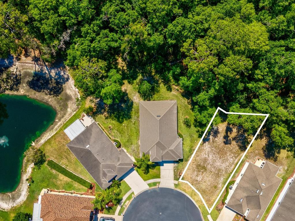 An aerial view shows a vacant residential lot next to two houses near a pond — 11444 MERGANSER WAY, NEW PORT RICHEY, FL