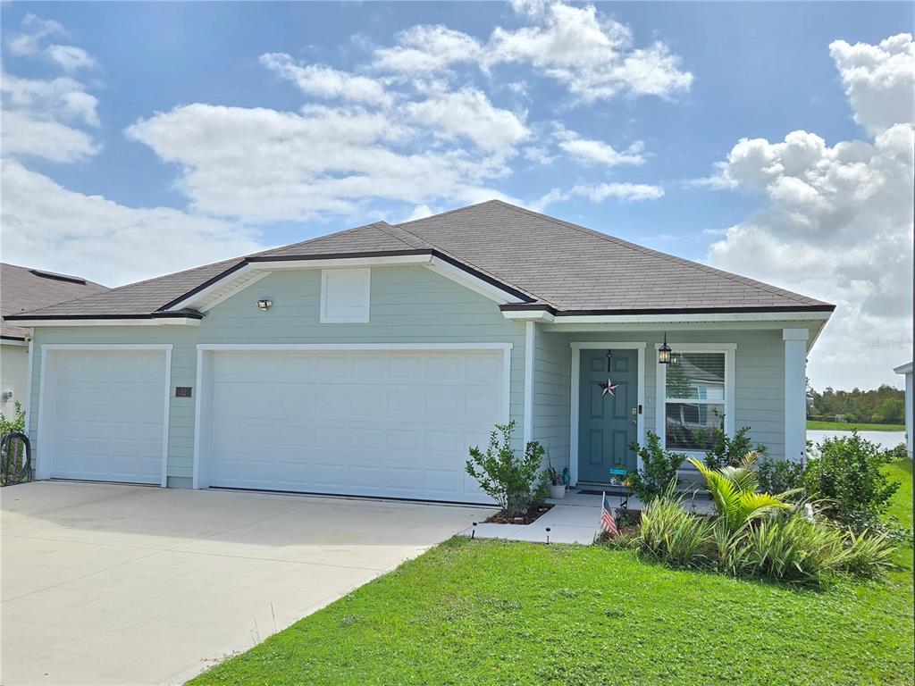 A light green single-story house with a three-car garage and a front entrance — 32 HULETT WOODS ROAD, PALM COAST, FL