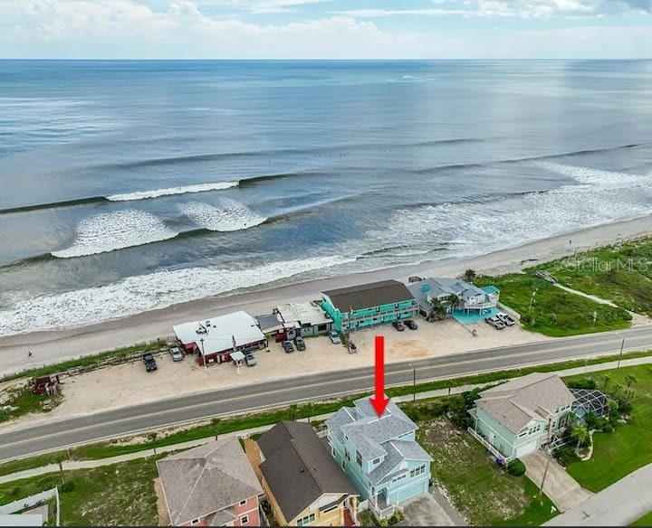 An aerial view shows a coastal house with a red arrow pointing to its roof — 2841 S CENTRAL AVENUE, FLAGLER BEACH, FL