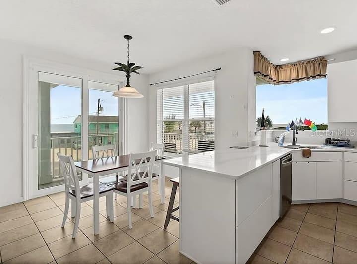 A kitchen and dining area with white cabinets, tile floors, and a sliding glass door — 2841 S CENTRAL AVENUE, FLAGLER BEACH, FL