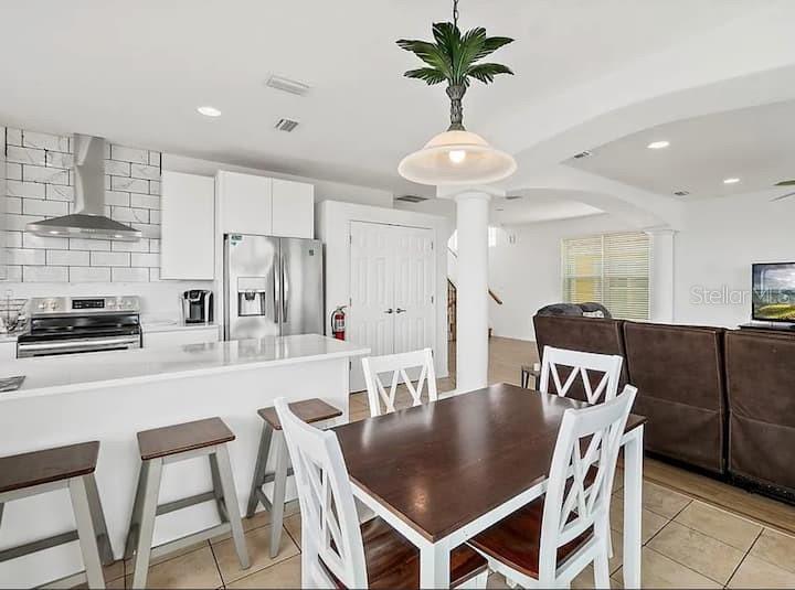 A kitchen with white cabinets and a dining area with a wooden table and chairs — 2841 S CENTRAL AVENUE, FLAGLER BEACH, FL