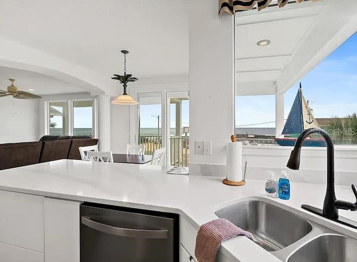 A kitchen island with a stainless steel dishwasher overlooks a dining area and ocean view — 2841 S CENTRAL AVENUE, FLAGLER BEACH, FL
