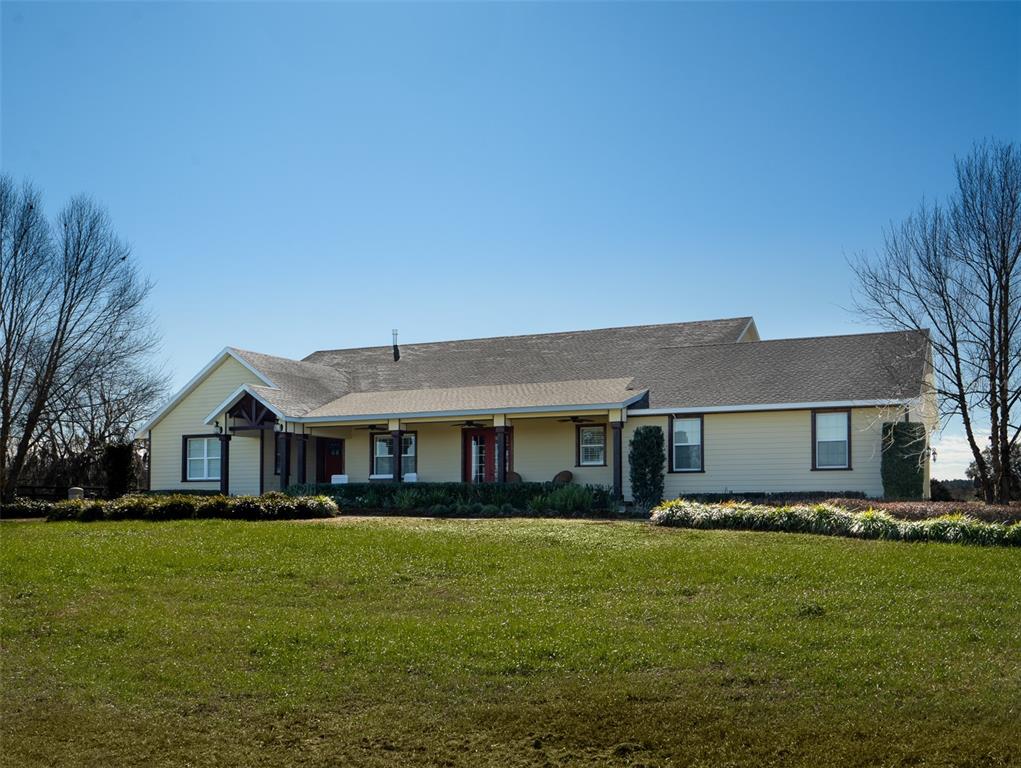 A yellow, single-story house with a covered porch sits behind a large green lawn — 11130/11122 W HIGHWAY 326, OCALA, FL
