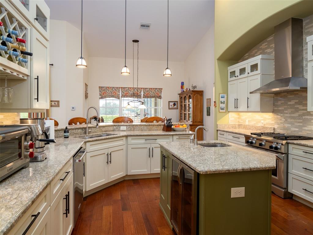 A kitchen with white cabinets, a green island, granite countertops, and stainless steel appliances — 11130/11122 W HIGHWAY 326, OCALA, FL