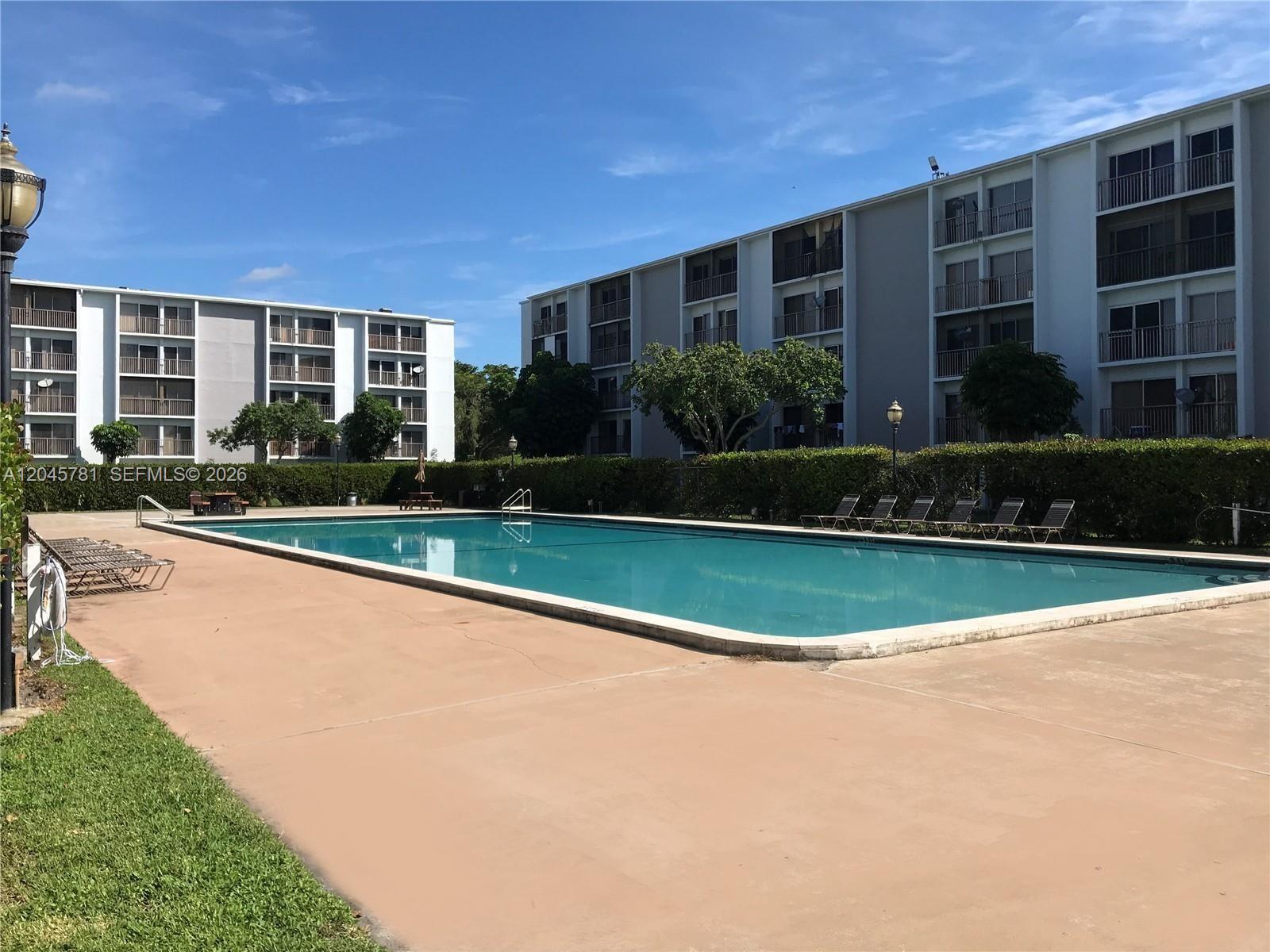 A kitchen features wood cabinets, stainless steel appliances, and gray countertops over tiled flooring — 8750 N Sherman Cir # 403, Miramar FL 33025, MIRAMAR, FL