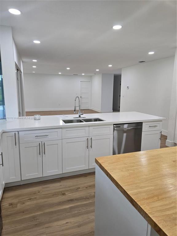 A kitchen features white cabinets, a stainless steel dishwasher, and a light wood countertop island — 4508 FIRE COURT, LABELLE, FL