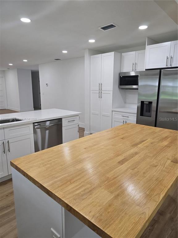 A kitchen features white cabinetry, stainless steel appliances, and a large wooden island countertop — 4508 FIRE COURT, LABELLE, FL