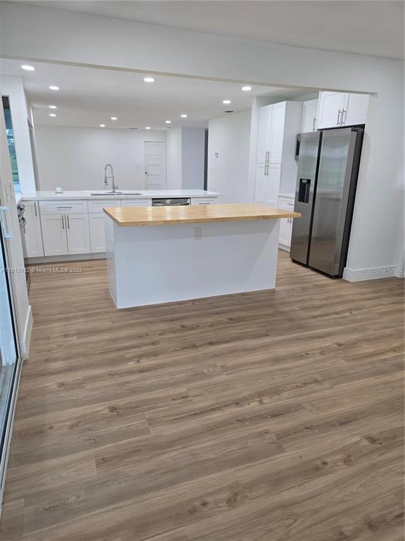 A kitchen features white cabinets, a wooden island countertop, and light wood-look flooring — 4508 FIRE COURT, LABELLE, FL