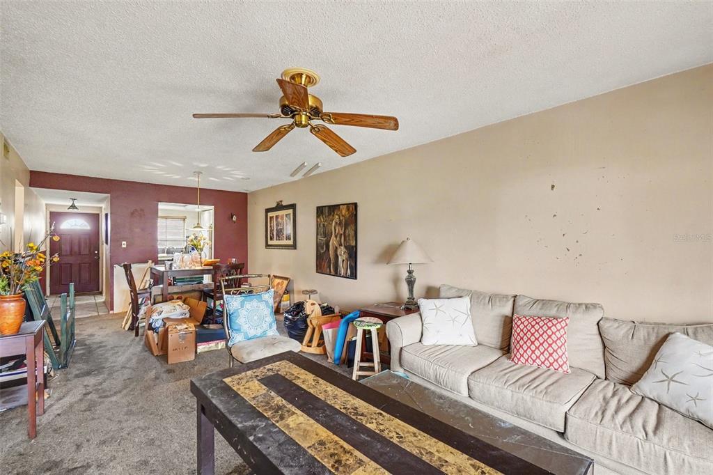 A living room with a beige sofa, a ceiling fan, and a dining area beyond — 4009 LAKE BAYSHORE DRIVE UNIT 105, BRADENTON, FL